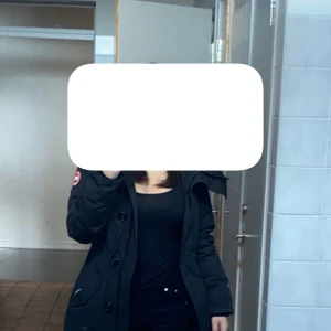 Svart dunjacka från Canada Goose XS - Säljer en svart dunjacka från Canada Goose i storlek XS. Jackan har klassisk design med stora knappar, dragkedja och fickor framtill. Perfekt för kalla dagar och har den ikoniska Canada Goose-loggan på ärmen. Knappt använd och går även att ha på sig som någon i storlek S💞 för mer frågor hör av dig💕