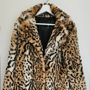 Leopardmönstrad fuskpälsjacka  - Fuskpälsjacka i leopardmönster från H&M. Jackan har en klassisk rak modell med bred krage, fodrad insida. Mjukt & varmt material, perfekt för både höst och vinter.   Strl. XS  Använd få gånger, Jackan är i fint skick förutom att det översta spännet saknas.