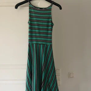 Randig grön klänning med öppen rygg - Grön klänning med rosa detaljer och öppen rygg. Säljer då den inte längre passar min stil, storlek XS men passar mig som vanligtvis har S.