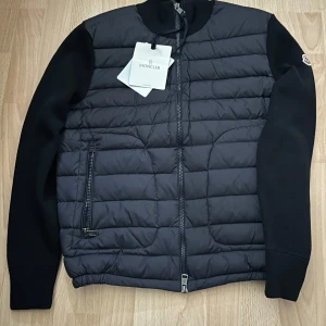 Mörk blå cardigan, Moncler  - Säljer en mörkblå Moncler cardigan i storlek S (passar även M) Jackan har quiltad front, stickade ärmar och Moncler-logga på ena ärmen. Dragkedja framtill och två fickor med dragkedja. Perfekt för dig som vill ha en stilren och exklusiv look. Speciellt nu t hösten och vintern. Pris kan diskuteras !!! Säljer den pga. Storleken! (Har st L)