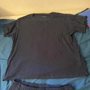 Mörkblå ribbad pyjamas  - Mörkblå pyjamas från nightwear med diskret ribbad struktur. Klassisk rund halsringning och korta ärmar. Pyjamasen är i mjukt material och har en enkel, stilren look. Perfekt för dig som gillar basic men ändå vill ha lite textur.