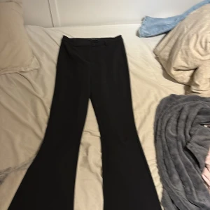 Svarta bootcut byxor från Vero Moda XS - Säljer ett par svarta bootcut byxor från Vero Moda i storlek XS/32. Byxorna har en klassisk svart färg, utsvängda ben och sitter snyggt i midjan. Perfekta till en trendig och stilren look. Materialet är mjukt och stretchigt för extra komfort.