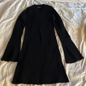 Svart ribbad klänning med trumpetärm - Svart ribbad klänning från stradivarius med lång trumpetärm och rund hals.
