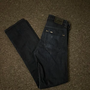 Mörkblå jeans från Lee - Snygga mörkblå jeans från Lee med klassisk design. De har en rak passform och är tillverkade i slitstarkt denim. Perfekta för en stilren look.