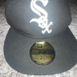 Svart New Era 59FIFTY White Sox keps - Säljer en svart New Era 59FIFTY keps med White Sox-logga broderad framtill i vitt. Klassisk flat peak och broderad New Era-logga på sidan. Kepsen är tillverkad i ett slitstarkt material och har en snygg, sportig look.