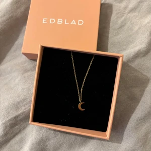 Guldigt månhalsband från Edblad - Snyggt halsband från Edblad med tunn kedja i guld och ett litet månhänge. Perfekt för dig som gillar minimalistiska smycken med en unik detalj. Levereras i original ask. 
