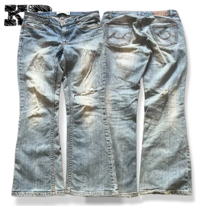 Ljusblåa Lågmidjade Jeans - Ljusblå bootcut jeans från JSFN denim med slitningar och trasiga detaljer på benet. Klassisk femficksmodell med snygga kontrastsömmar och broderade bakfickor. Jeansen har en avslappnad passform och är tillverkade i bomull.