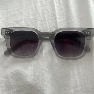 Grå CHIMI 04.2 solglasögon - Säljer ett par stilrena CHIMI 04.2 solglasögon i grått med rektangulär form. Glasögonen har en modern design och kommer med originalbox och putsduk. Perfekt accessoar för dig som gillar minimalistisk look och vill ha något som sticker ut.