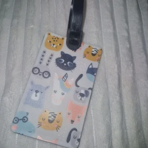 Resväsktag  - Ny reväsktag med gulliga djuransikten i olika färger och mönster på framsidan. Taggen har en svart rem för enkel fastsättning och plats för kontaktuppgifter på baksidan. Perfekt för att göra din väska personlig och lätt att hitta.