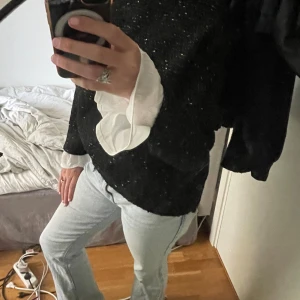 Tröja - Säljer en svart stickad tröja från Taranko med guldglittriga detaljer. Tröjan har lång ärm och en klassisk passform. Perfekt för dig som vill ha något extra snyggt och unikt i garderoben.