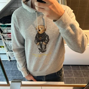 Grå hoodie Polo Bear från Polo Ralph Lauren - Tja, säljer nu min gråa hoodie från Ralph lauren. Säljer då den blivit lite för liten för mig. Har ett litet slitage på höger armbåge (inget som märks, se bild 4) där av priset.