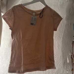 Ljusrosa t-shirt från H&M, stl S - Enkel och stilren ljusrosa t-shirt från H&M i storlek S. T-shirten har rund halsringning och korta ärmar. Tillverkad i mjuk bomull som känns skön mot huden. Perfekt att matcha med jeans eller kjol för en avslappnad look.