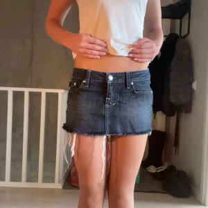 Mörkblå jeanskjol från Rock & Republic - Säljer en mörkblå jeanskjol från Rock & Republic med rå kant och slitna detaljer. Kjolen har klassiska fickor fram och bak, med snygga broderade R på bakfickorna. Perfekt för dig som gillar streetstyle och denim.