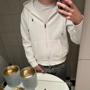 Vit Polo Ralph Lauren kofta - En vit Polo Ralph Lauren zip-kofta. Den är i jättebra skick och har använts MAX 2-3 gånger så den är som gott som ny. Den passar till nästan allt och är en allmänt snygg kofta. Ordinarie pris på den när jag köpte den var 2000 kr cirka. Säljer denna också på Vinted. Hör av er om ni har frågor!