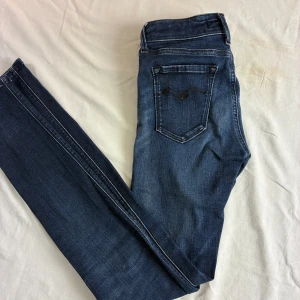 Replay LUZ skinny jeans blå, stl 24 - Snygga blå skinny jeans från Replay, modell LUZ. Klassisk femficksdesign med mörkblå tvätt och diskreta slitningar. Jeansen har normal passform och är tillverkade i stretchigt denim för en bekväm känsla. Perfekta för dig som gillar en smal siluett. W24 L30