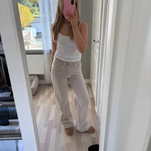 Beiga raka jeans med låg midja - Säljer ett par beiga jeans med låg midja och raka ben. Jeansen har klassisk femficksdesign och är tillverkade i ett mjukt bomullstyg. Perfekta för en avslappnad och trendig look.