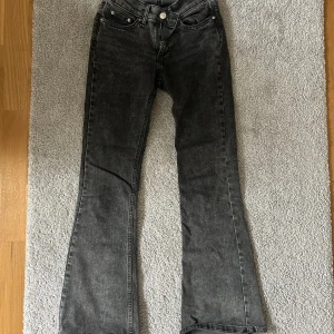 Grå bootcut jeans från Gina Tricot - Snygga grå/svarta jeans från Gina Tricot, modell Perfect Jeans. De har en bootcut passform med lätt utsvängda ben. Jeansen är i ett tvättat grått denimtyg och har normal midja. Helt nytt skick, bara använd ett par gånger. Jag är ca 155cm lång och jeansen går perfekt över mina skor! 