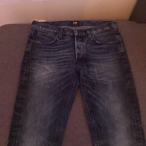 Mörkblå Lee Austin jeans W32 L32 - Säljer ett par mörkblå Lee Austin jeans med snygg tvätt och klassisk femficksdesign. Jeansen har raka ben och normal passform, tillverkade i slitstarkt bomullstyg. Perfekta för dig som gillar en tidlös look med lite faded detaljer.