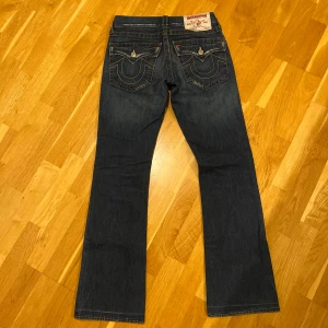 True Religion Jeans - Sektion: Billy (bootcut)  Storlek: 27 (mäts till ungefär 29”)  Skick: Mycket bra, förutom en liten defekt vid fållen som vidas på sista bilden. Inte märkbart alls när man har dem på.  Tveka inte att höra av dig om du har några fler frågor!