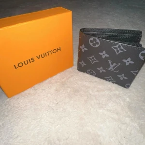 Svart handväska med orange box - Snygg svart handväska med stilren design och detaljer i silver. Kommer med en ikonisk orange box som ger exklusiv känsla. Perfekt storlek för det viktigaste och passar till många outfits.