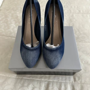 Mörkblå jeanspumps från L.S - Snygga pumps i mörkblå denim från L.S med spetsig tå och smal klack i trälook. Skorna har en klassisk siluett och är tillverkade i jeansmaterial som ger en cool och modern känsla. 