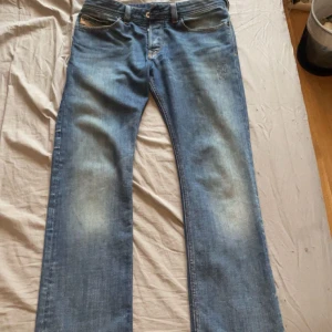 Diesel industry jeans - Säljer ett par klassiska blå jeans från Diesel Industry med raka ben och snygga slitningar framtill. Jeansen har fem fickor, kontrastsömmar och en cool tvättad look. Perfekta för dig som gillar en avslappnad och tidlös stil.