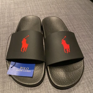 Ralph lauren tofflor - Säljer detta paret Ralph lauren tofflor som legat länge i garderoben och aldrig är använda. Det är i storlek 42. Tyvärr har jag inte kvar boxen till tofflorna pga att jag slängde den när jag fick hem tofflorna. Nypriset på detta paret ligger runt 1000kr