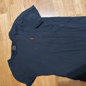 Svart t-shirt från Polo Ralph Lauren - Svart t-shirt från Polo Ralph Lauren med klassisk röd broderad logga på bröstet. T-shirten är i mjuk bomull och har en normal passform med korta ärmar. Perfekt basic-plagg med stilren look.