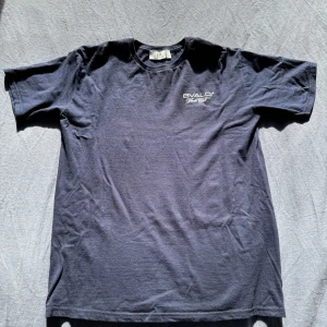 Marinblå Bvaldi Yacht Club t-shirt - Snygg marinblå t-shirt från Bvaldi Yacht Club med tryck av en färgglad båt på ryggen och logga på bröstet. Klassisk rund hals och korta ärmar. Perfekt för dig som gillar en chill och sportig stil.