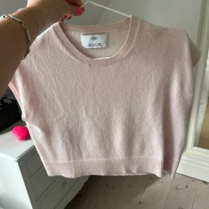 Ljusrosa stickad topp från Allude - Supersöt ljusrosa stickad topp från Allude i mjuk kashmir. Croppad modell med ribbad kant och rund halsringning. Perfekt att styla med jeans eller kjol för en chill och trendig look.