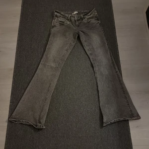 Grå bootcut jeans från Gina Tricot - Säljer ett par gråa bootcut jeans från Gina Tricot i storlek S. Jeansen har klassisk femficksdesign, bälteshällor och en snygg tvättad look. Materialet är jeans och passformen är normal med utsvängda ben nertill.