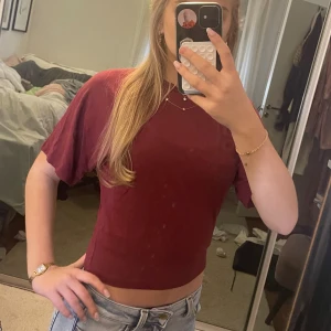 Vinröd croppad topp från 157 - Säljer en vinröd croppad topp från 157 med korta ärmar och rund hals. Enkel och stilren design som är lätt att matcha med jeans eller kjol. Tunt och mjukt material som känns skönt mot huden.