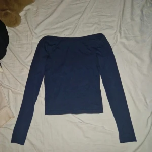 Mörkblå långärmad topp från Kappahl - Säljer en stilren mörkblå långärmad topp från Kappahl. Toppen har en offshoulder-design med smal passform och är tillverkad i mjuk bomull. Perfekt för dig som gillar enkla och snygga basplagg med en modern touch.