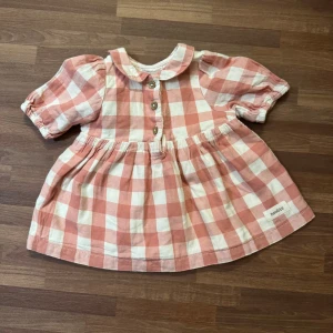 Rutig klänning - Supersöt kortklänning från Newbie i rosa och vitt rutigt mönster. Storlek 56 (1-2mån), använd väldigt fåtal gånger helt utan anmärkningar.