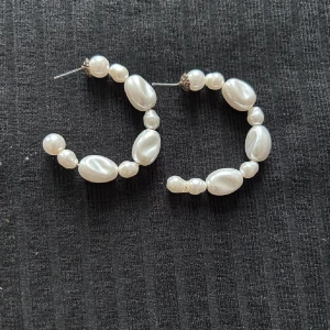 Hoop-örhängen med pärlor - Säljer ett par snygga hoop-örhängen med vita pärlor i olika storlekar och former. De har en rund form och ger en elegant vibe till din look. Perfekt för dig som gillar klassiska smycken med en twist. Saknar pluppar 