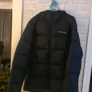 Columbia svart vinter jacka stl M - Svart vadderad jacka från Columbia med luva och dragkedja. Jackan har Columbias Omni-Heat teknologi.