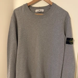 Grå sweatshirt från Stone Island - Säljer en grå sweatshirt från Stone Island. Ikonisk svart patch i bra skick på vänster ärm. Mjuk bomullskvalitet. Den är strl M med en normal till något större passform. Perfekt för chill dagar eller finare tillfällen. Nypris ligger på omkring 3000kr.