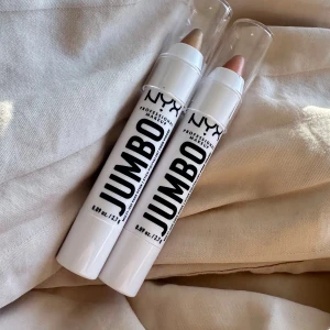 NYX Jumbo Multi-Use Face Sticks - Två NYX Jumbo Multi-Use Face Sticks i pennformat med twist-up. Ena sticken är skimrande champagnefärgad och den andra är roséguldig. Perfekta som highlighter eller ögonskugga. Plastförpackning med genomskinligt lock, smidiga att ta med i väskan.