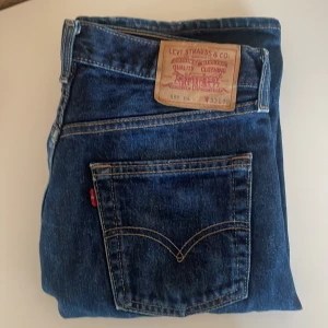 Levi's 555 blå jeans straight fit - Klassiska Levi's 555 jeans i blå denim med raka ben och normal passform. Byxorna har fem fickor, knappgylf och den ikoniska läderpatchen bak i midjan. Perfekta för dig som gillar tidlös stil och vill ha ett par jeans som funkar till allt.