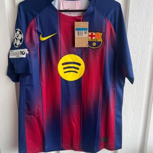 FC Barcelona matchtröja Roony 28 Nike - Säljer en officiell FC Barcelona matchtröja från Nike med Roony och nummer 28 på ryggen. Tröjan är blå och röd med gula detaljer, randigt mönster och klubbmärke på bröstet. Champions League-märke på ärmen och Spotify-logga på framsidan. Tillverkad i lätt funktionsmaterial.