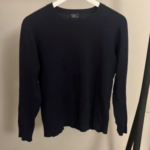 Mörkblå cashmeretröja - Mörkblå tröja i storlek S. Tillverkad i en lyxig mix av 85% silke och 15% kashmir, vilket gör den supermjuk och skön. Klassisk rund halsringning och långa ärmar, perfekt för lager-på-lager under kyliga dagar.
