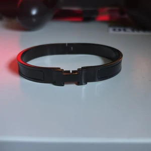 Svart  armband - Stilrent armband i svart och silverfärgad metall med en modern, kantig design. Armbandet har en smidig låsmekanism och en slät yta som ger en cool och minimalistisk vibe. Perfekt för dig som gillar enkla accessoarer med edge.