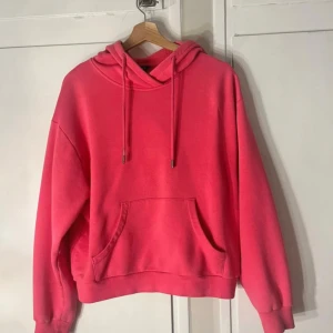 Rosa hoodie från Lindex - Säljer en snygg rosa hoodie från Lindex i storlek S. Tröjan har huva med snörning, magficka och ribbade muddar vid ärmslut och nederkant. Perfekt för chill dagar eller när du vill vara extra comfy.