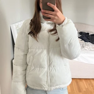 Vit pufferjacka från Stories XS - Säljer en vit pufferjacka från Stories i storlek XS. Jackan har dragkedja framtill, hög krage och två fickor med dragkedja på sidorna. Perfekt för kyligare dagar och ger en snygg, puffig siluett.