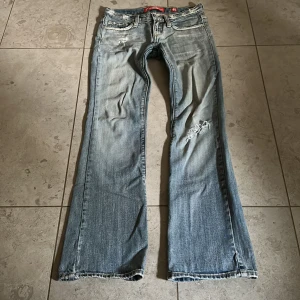 Ljusblå lågmidjade bootcutjeans  - Så snygga ljusblå lågmidjade jeans från Fracomina med slitna detaljer och bootcut-ben. Jeansen har klassisk femficksdesign, låg midja och coola slitningar framtill och på fickorna. Perfekta för en avslappnad och trendig look. Midjemått tvärsöver: 36 cm. Innerbenslängd: 80 cm. Det står storlek 40 i lappen men sitter som en XS. Kolla måtten! 