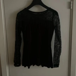 Svart spetsblus från cubus- storlek 146/152 - Elegant svart topp från Cubus i stolek 146/152. Den har långa spetsärmar och ett lätt utsvängt fall nedtill. Ärmarna är genomskinliga med ett vackert spetsmönster, medan kroppen är fodrad för teckning. Perfekt för både vardag och fest😊