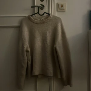 Beige stickad tröja från Gina Tricot - Mysig beige stickad tröja från Gina Tricot med rund halsringning och ribbade muddar. Perfekt för lager-på-lager och chill höst- eller vinterstil. Enkel och stilren design som funkar till allt.