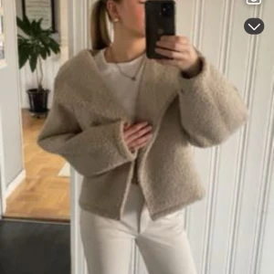 Beige teddyjacka med oversized passform - Supermjuk och fluffig beige teddyjacka med bred krage och oversized passform. Jackan är croppad och har långa ärmar, perfekt för att hålla sig varm och snygg under kyliga dagar. 