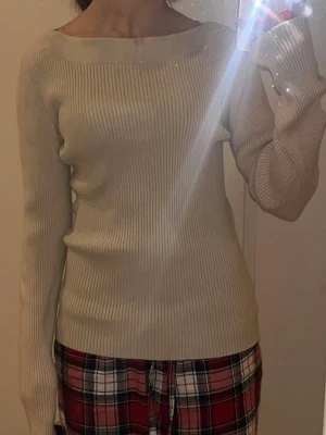 Beige ribbad tröja från Kappahl - Säljer en beige ribbad tröja från Kappahl med bred, båtringad hals och lång ärm. Tröjan har en slim passform och är tillverkad i mjukt stickat material som sitter snyggt på kroppen. Perfekt till både jeans och kjol.