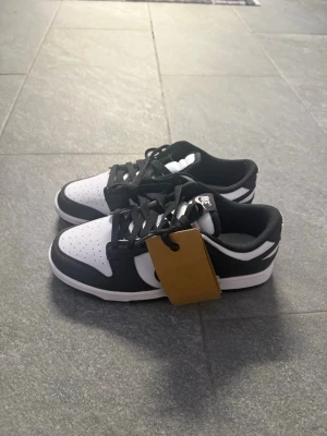 Nike Dunk Low svart/vit sneakers - Nike Dunk Low sneakers i svart och vitt med klassisk snörning och rund tå. Skolek 39. Aldrig använda helt nya 💕